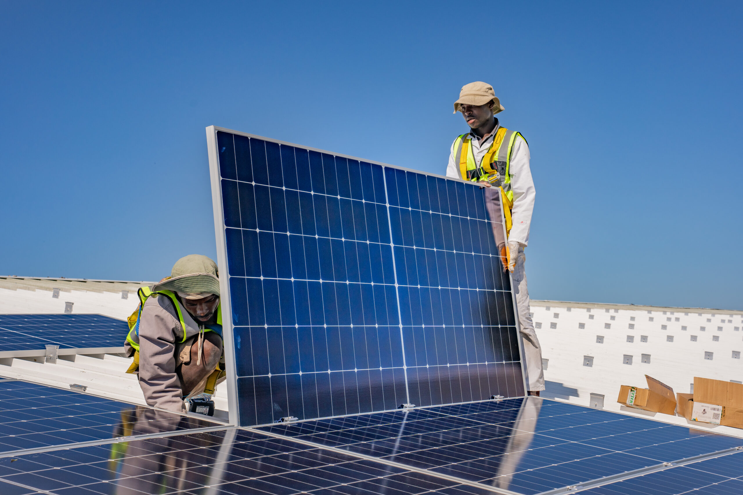 Arbeiter installieren Solarpanels auf einem Schuldach